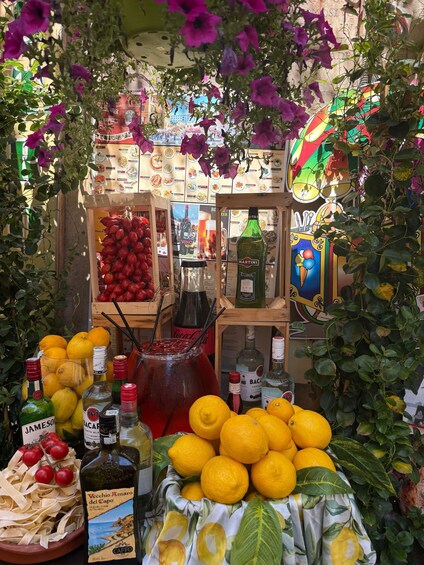 A market stall with lemons, tomatoes, and various bottles of alcohol. 2
