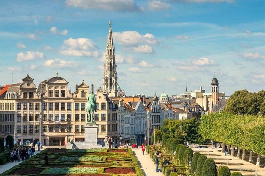 Stadsgezicht met historische gebouwen, een opvallende kerktoren en een verzorgde tuin. 1