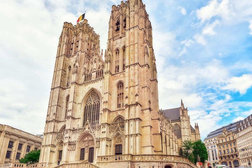 Een grote gotische kathedraal met twee hoge torens, een vlag en een heldere lucht. 5