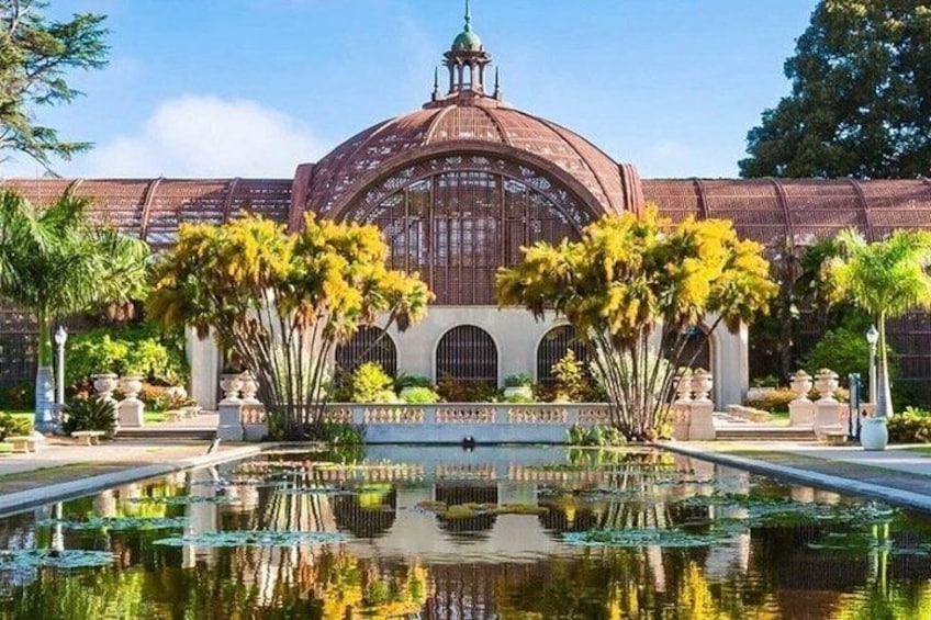 Un bâtiment en forme de dôme dont l’image se reflète dans un bassin d’eau, le tout étant entouré de palmiers. 4