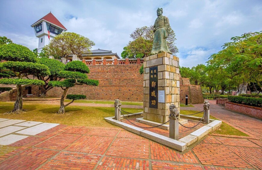 A statue in a courtyard with brick walls and trees. 4