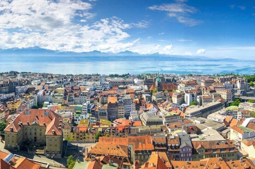 A panoramic view of a historic city with a river, mountains, and a clear sky. 4