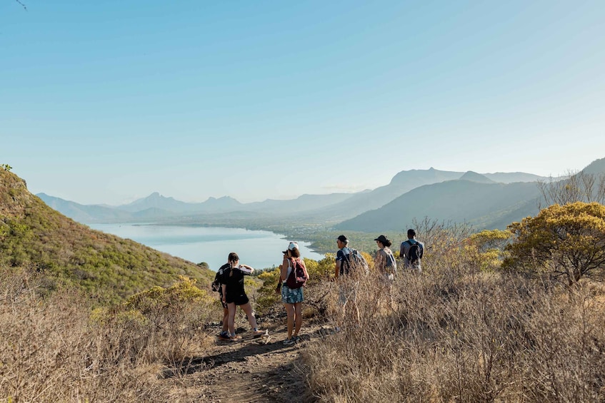 A group of hikers on a trail with a lake and mountains in the background. 1