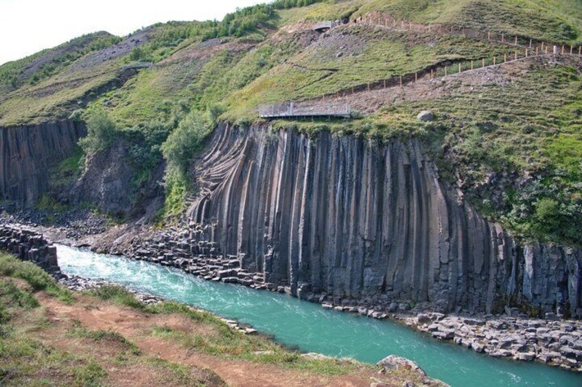 A river flowing through a canyon with steep cliffs and a wooden fence along the top. 2