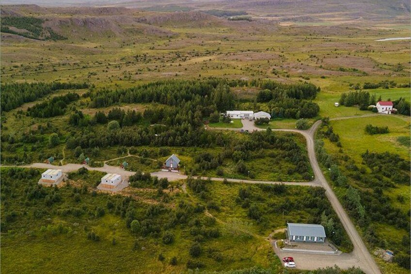 A rural landscape with scattered houses, a winding road, and a mix of open fields and dense vegetation. 5