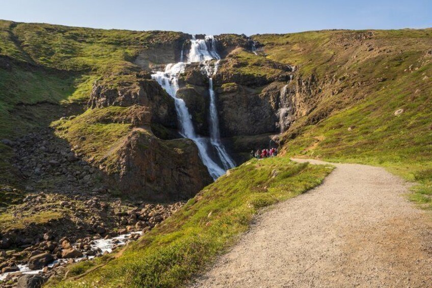 A waterfall, a gravel path, and a grassy hillside. 5