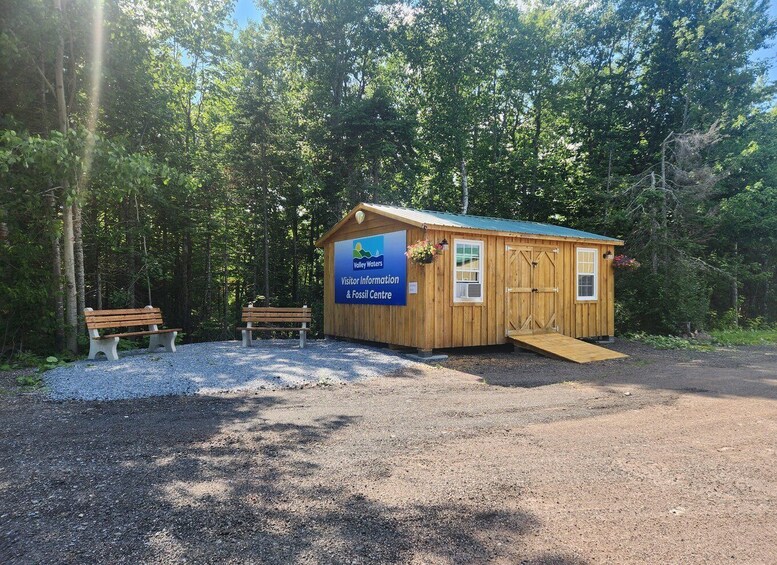 A wooden visitor center with a ramp, a bench, and surrounded by trees. 4