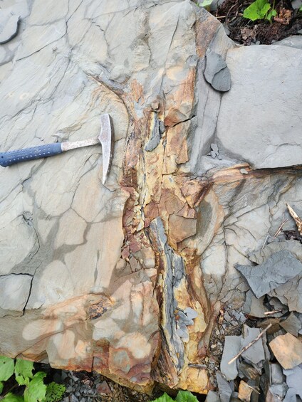 A hammer and chisel on a rock surface with visible cracks and layers. 5