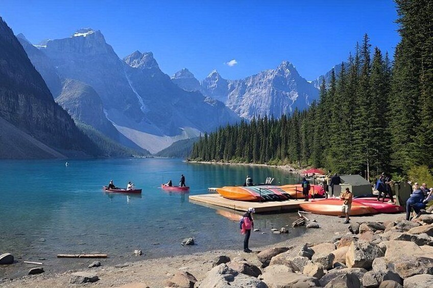 A lake with boats, a rocky shore, and mountains in the background. 4