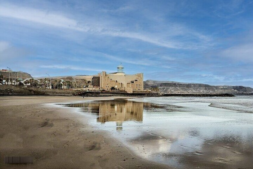 A desert landscape with a reflective water body, a building with a dome, and distant hills. 5