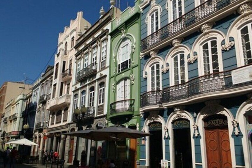 A row of colorful buildings with ornate balconies and a clear blue sky. 4
