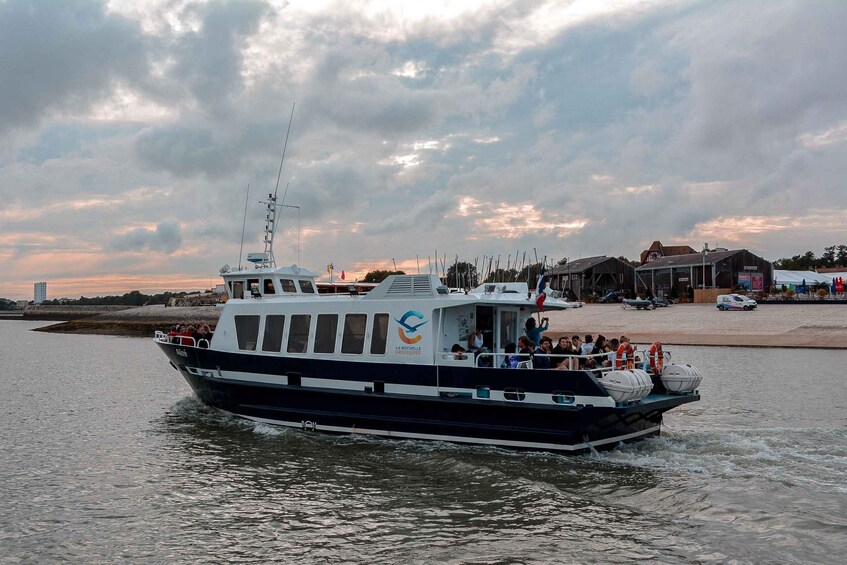A boat with passengers, a waterfront, and buildings in the background. 2