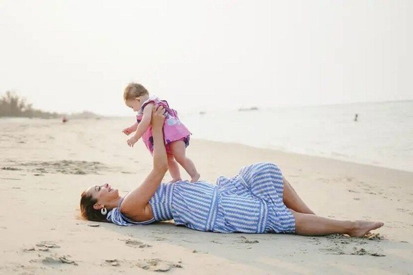A person lying on the beach with a child standing on their back. 5