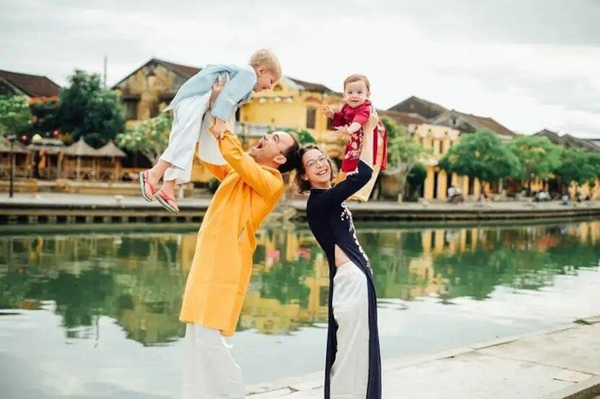 A family playing by a calm body of water with traditional buildings in the background. 4
