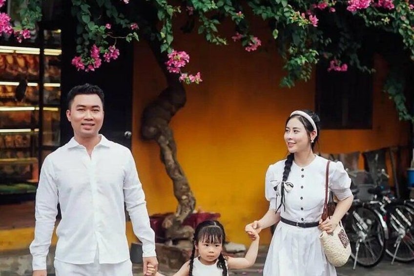A family walking under a flowering tree with a yellow building in the background. 3