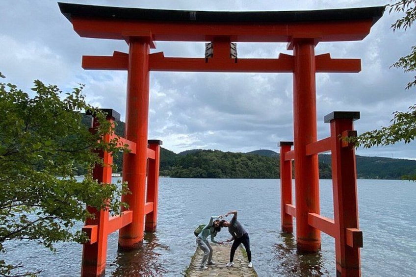 En röd torii-port över ett vattenområde, med två personer som interagerar i närheten. 3