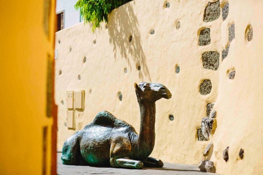 A camel sculpture on a textured wall. 1
