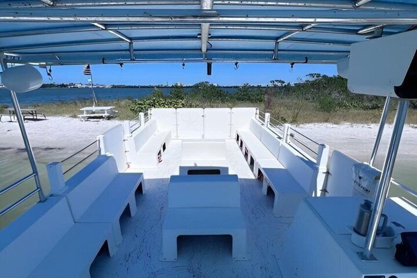 A boat deck with a covered area, seating, and a view of the beach and water. 2