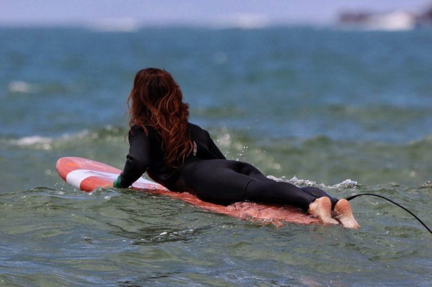 En person i våddragt sidder på et surfboard i havet. 4