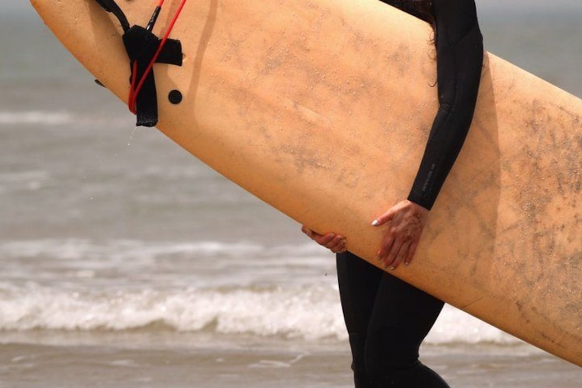 En person holder en surfbræt ved stranden. 5