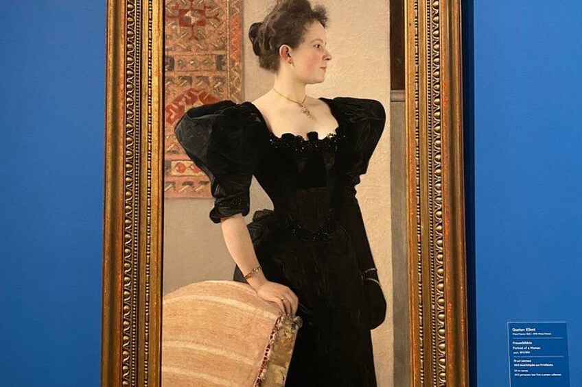 A person in a black dress with puffed sleeves standing in front of a mirror. 1