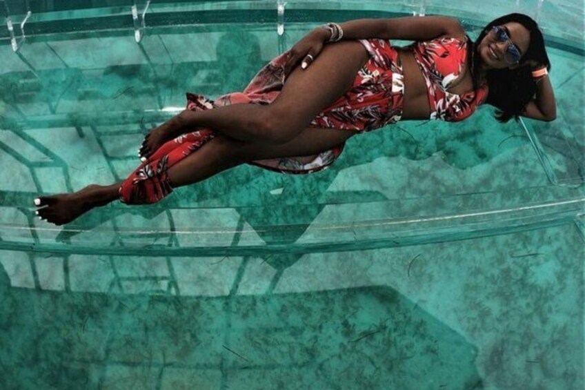 Una persona che fluttua in una piscina trasparente, indossa un costume da bagno rosso e nero. 3