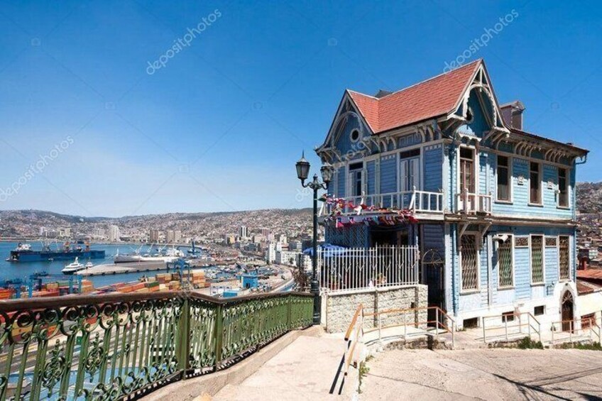 A coastal town with a prominent blue building overlooking a harbor with ships. 4