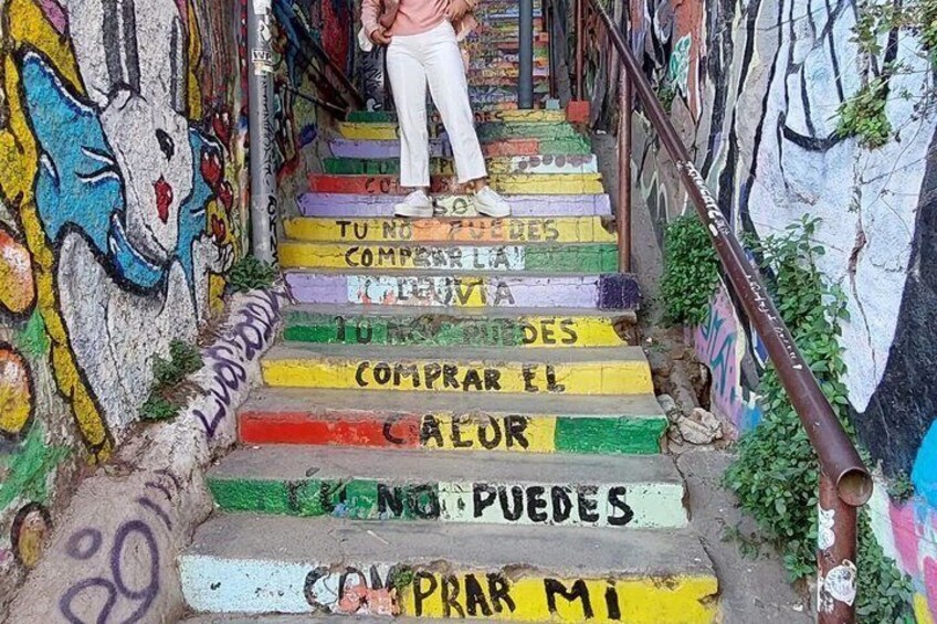 A staircase with colorful steps and graffiti, leading up to a person standing at the top. 5