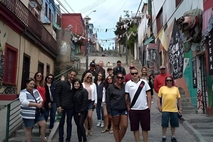 A group of people standing on a narrow street with buildings on either side. 1