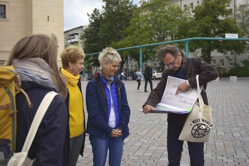 A group of people standing on a paved area with a building in the background. 2