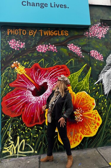 A mural with a large red flower and a person standing in front of it. 4