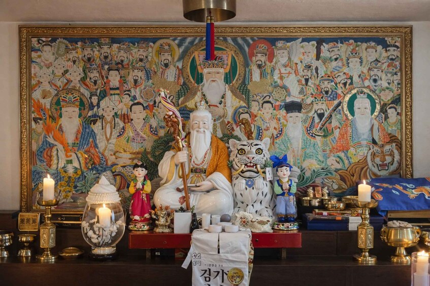 A traditional altar with statues, candles, and a large mural. 3