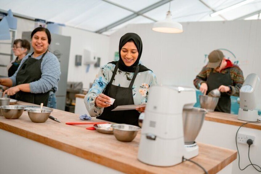 Een keuken met mensen die eten bereiden, een koffieapparaat en diverse kookgerei op het aanrecht. 5