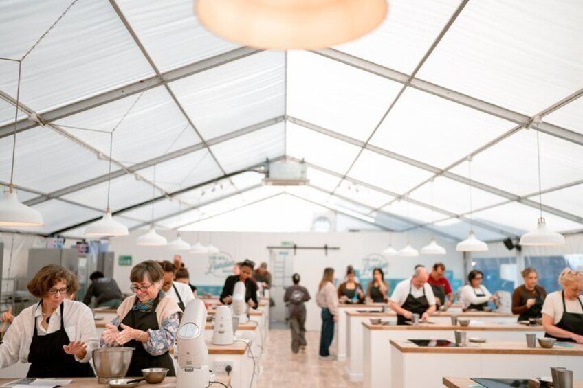 Een overdekte markt met eten, waar mensen koken en gerechten uitdelen. 4
