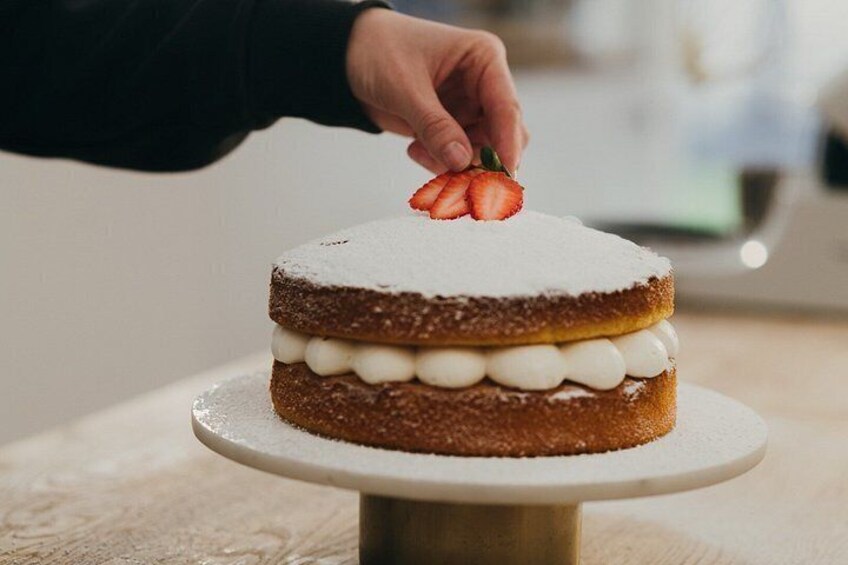 A cake with a hand placing a strawberry on top. 3