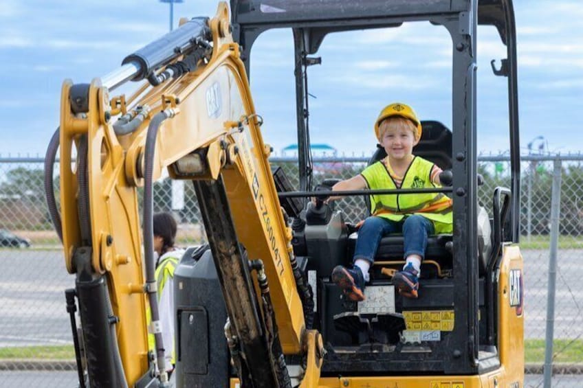 Una persona con giubbotto e casco giallo all'interno di un veicolo da cantiere giallo. 4