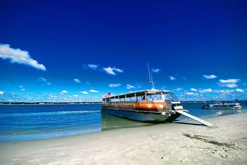 A boat named 'BISMAR' on a sandy beach with calm water and a clear blue sky. 1