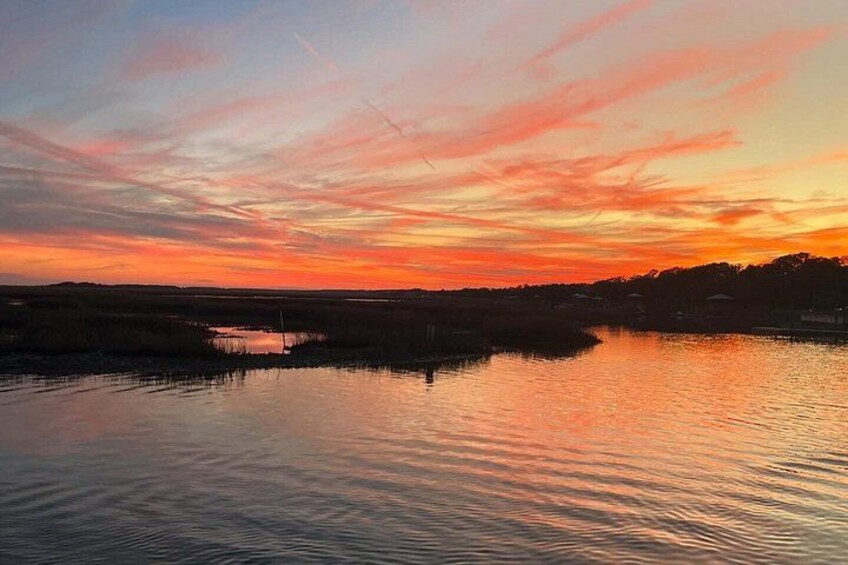 Un coucher de soleil sur une étendue d'eau calme, avec une côte lointaine à l'horizon. 2