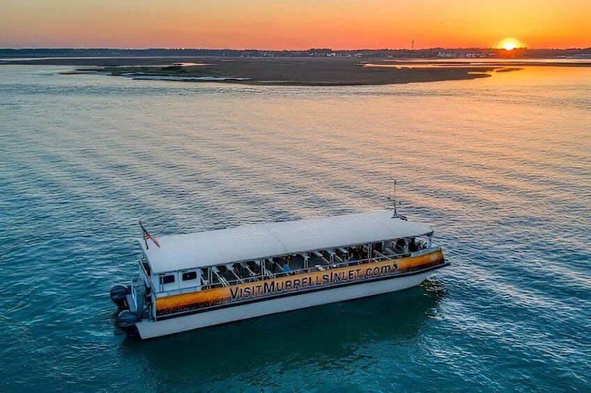 Un bateau sur lequel on peut lire les mots « VISIT MURRALL » sur le côté, flottant sur une eau calme au coucher du soleil. 1