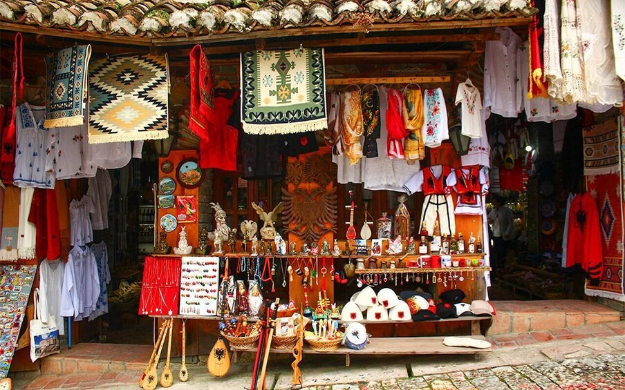 A traditional market stall with textiles, jewelry, and wooden crafts. 3