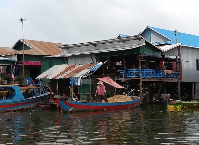 A floating house with a person walking by, boats docked nearby, and a waterway. 4