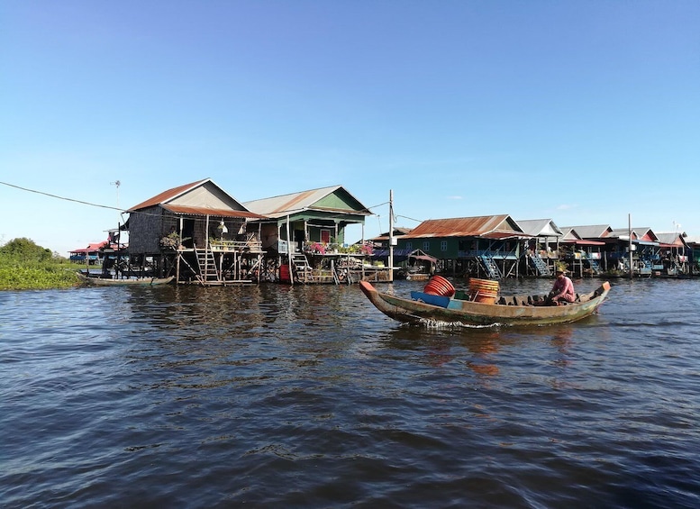 A traditional wooden boat on water, surrounded by floating houses with thatched roofs. 2