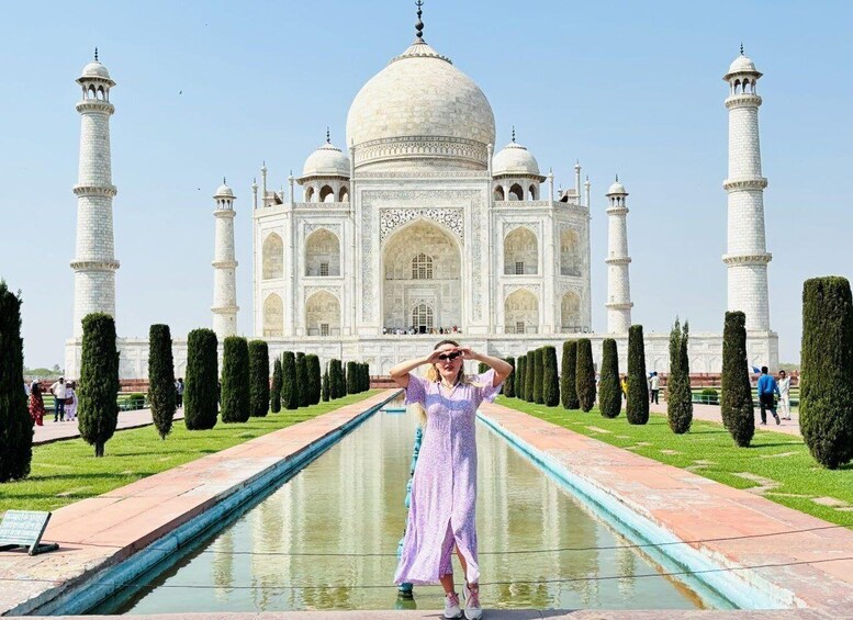 A person standing in front of the Taj Mahal with a clear view of the iconic white marble mausoleum and its four minarets. 2