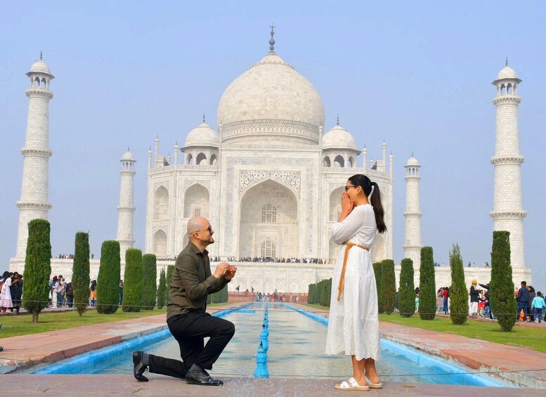 A man kneeling with a ring, proposing to a woman in front of the Taj Mahal. 2