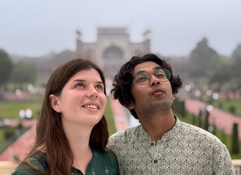 Two people standing in front of a large historical monument with a garden in the background. 3