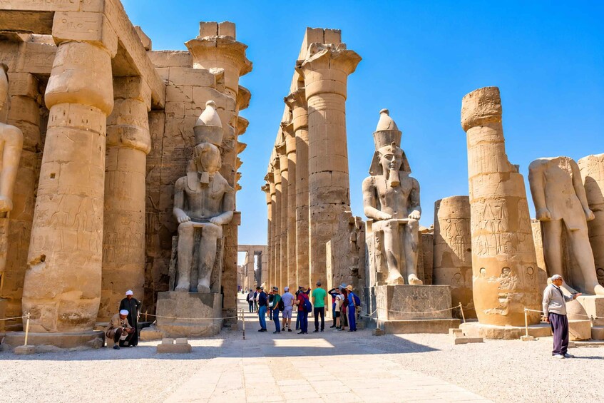 Ancient Egyptian temple ruins with large statues and hieroglyphs. 4