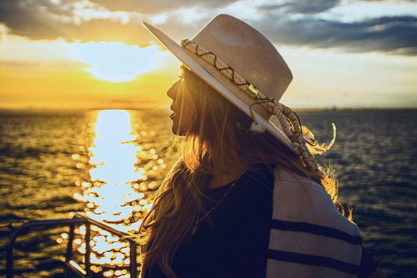 A person with a hat overlooking a body of water at sunset. 4