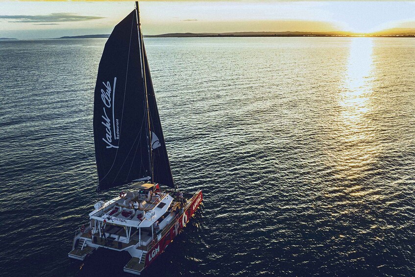 A sailboat with a black sail on a calm sea at sunset. 2