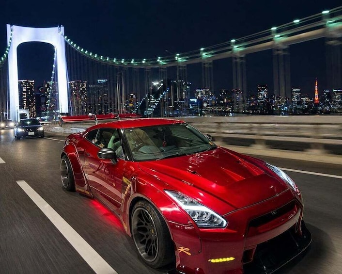 A red sports car driving on a bridge with city lights in the background. 3
