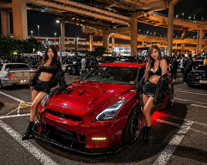 A red sports car parked in a busy parking lot at night. 2